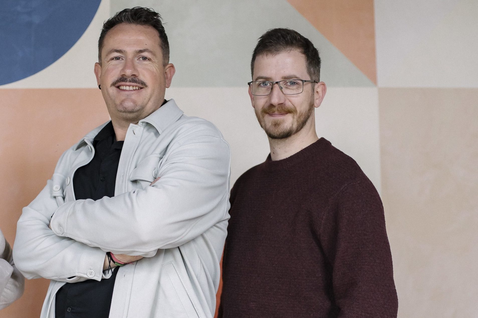  Trois personnes souriantes devant un mur coloré.